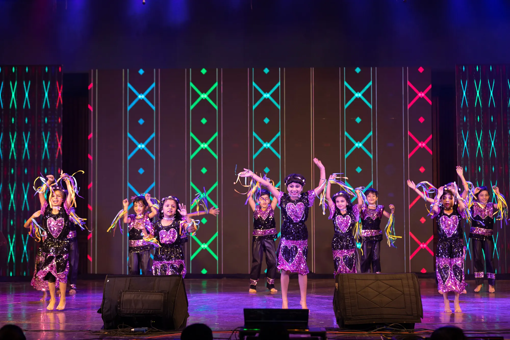 Students in purple costumes dancing on stage at Annual Day